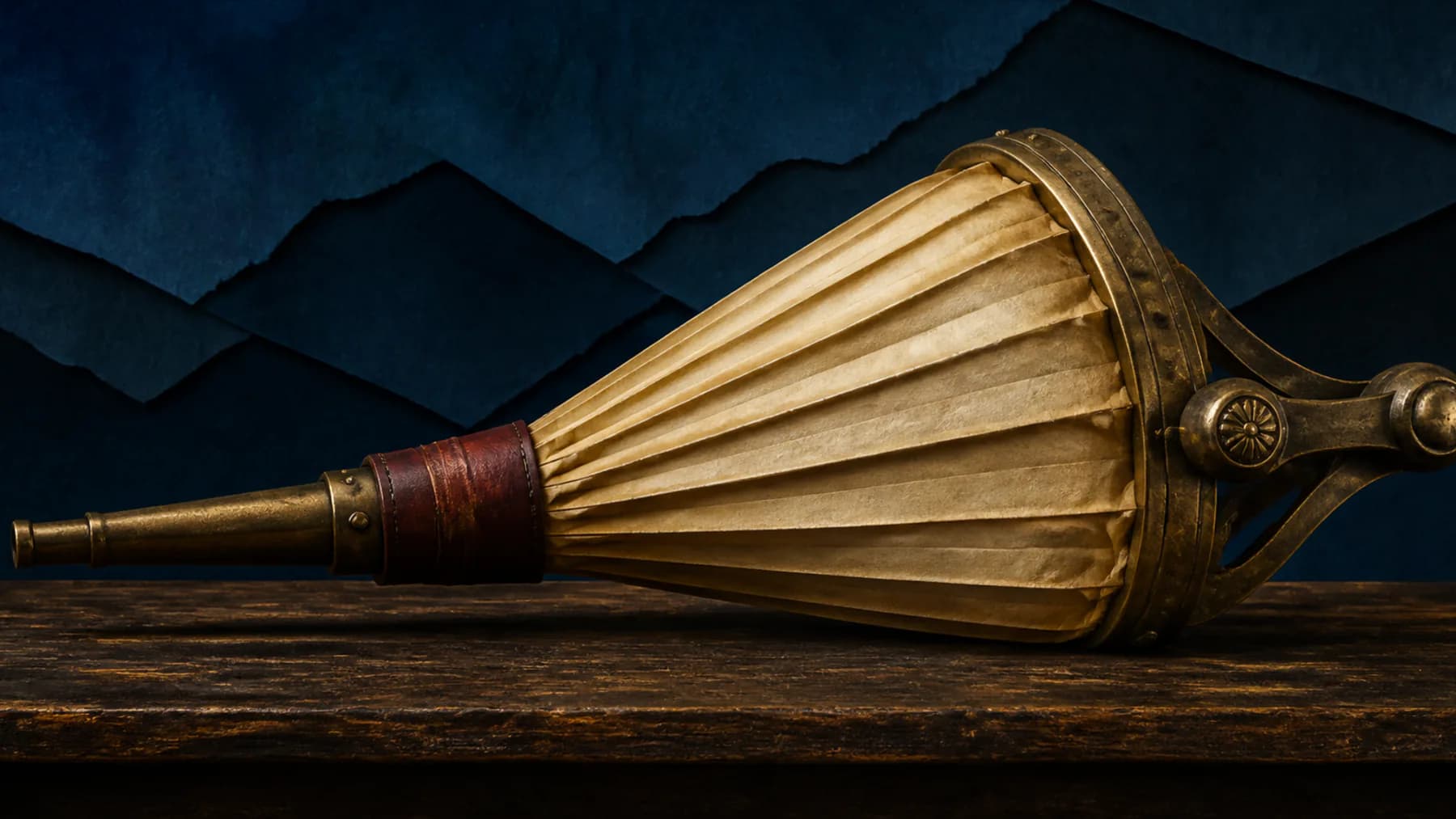 An antique brass forge bellows with broad cream paper folds held by a narrow oxblood leather band against layered midnight-blue paper.